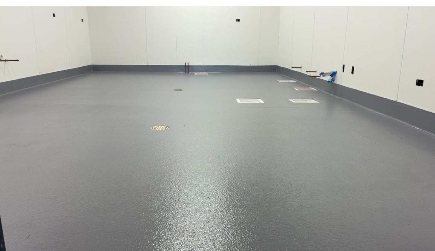 Freshly coated gray epoxy floor in a commercial buildout